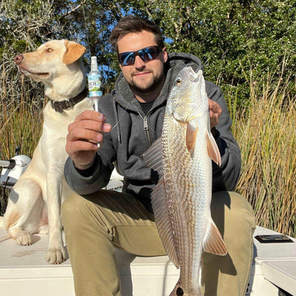 Person holding a Busch Light Beer fishing bobber while sitting on his boat with his dog